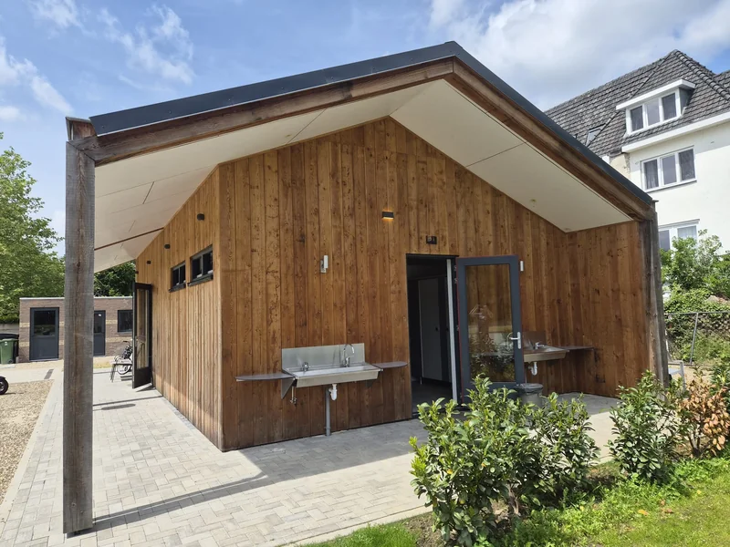 Sanitair gebouw met houten gevel en buitenwasplek